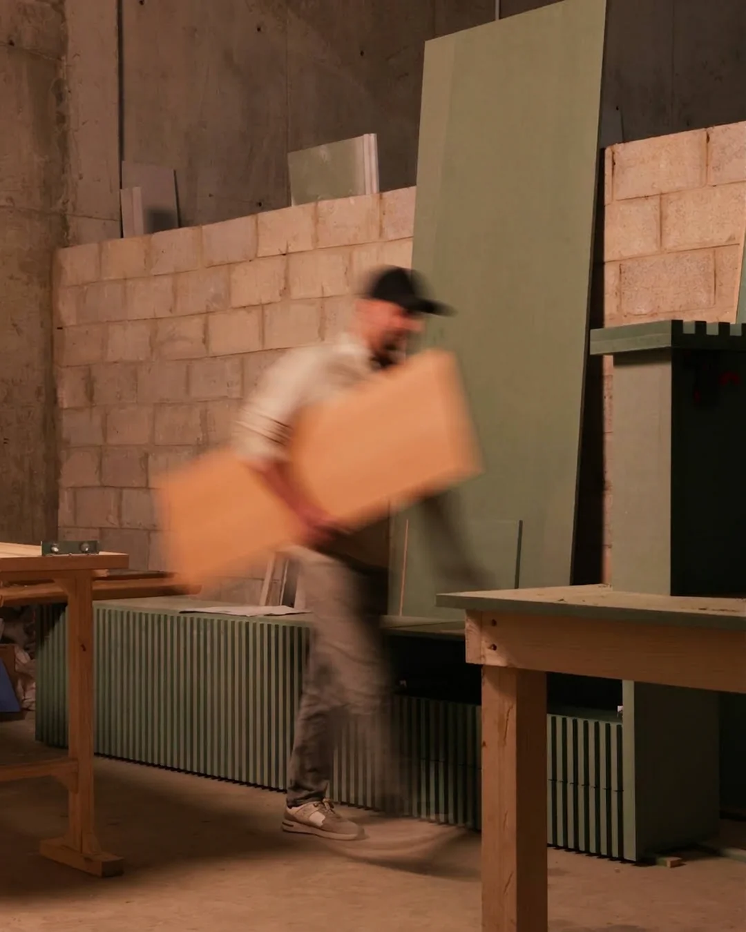 A maker carrying a panel across the workshop floor
